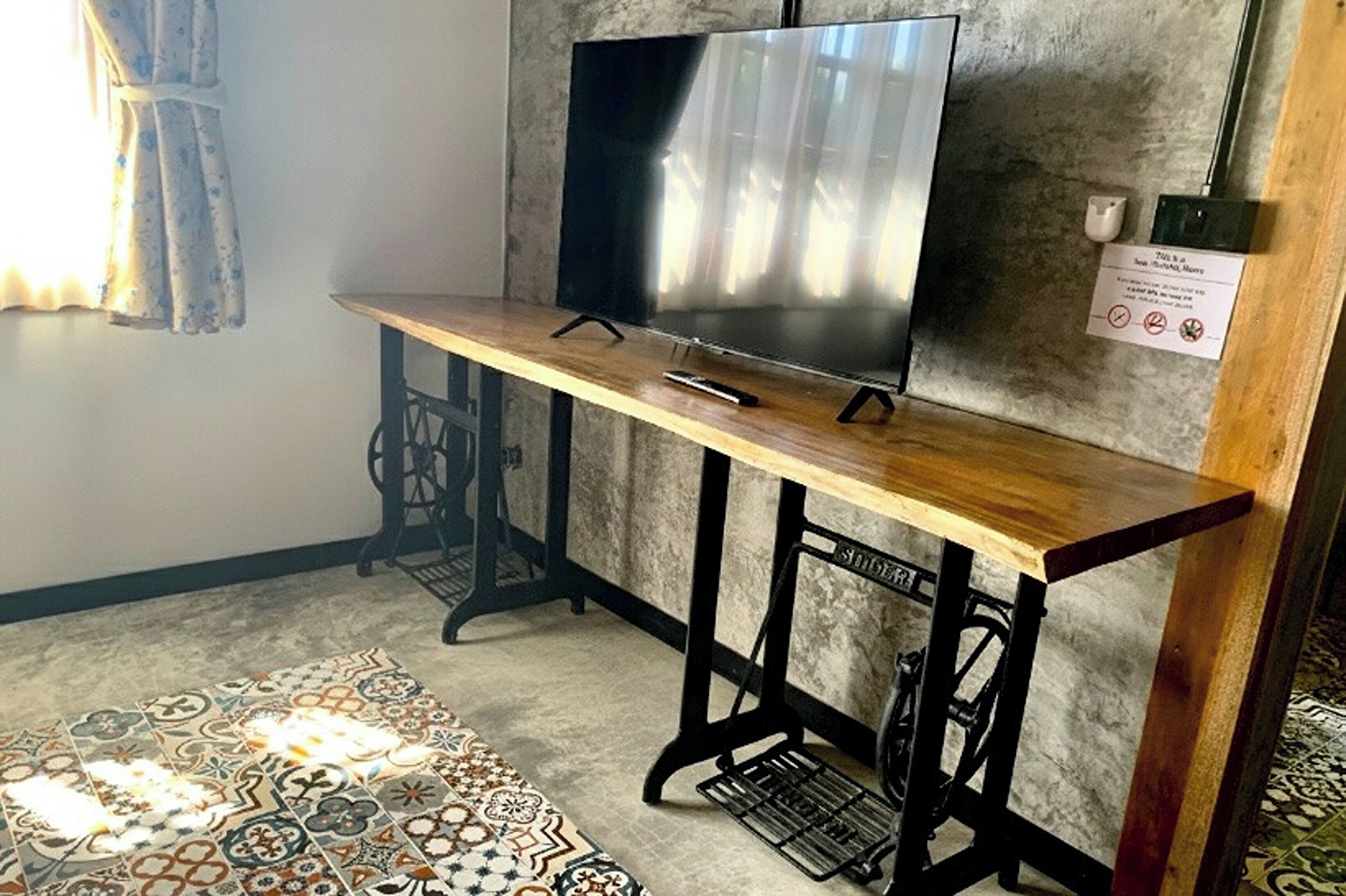 Una habitación con una mesa de madera, un televisor y una alfombra estampada.