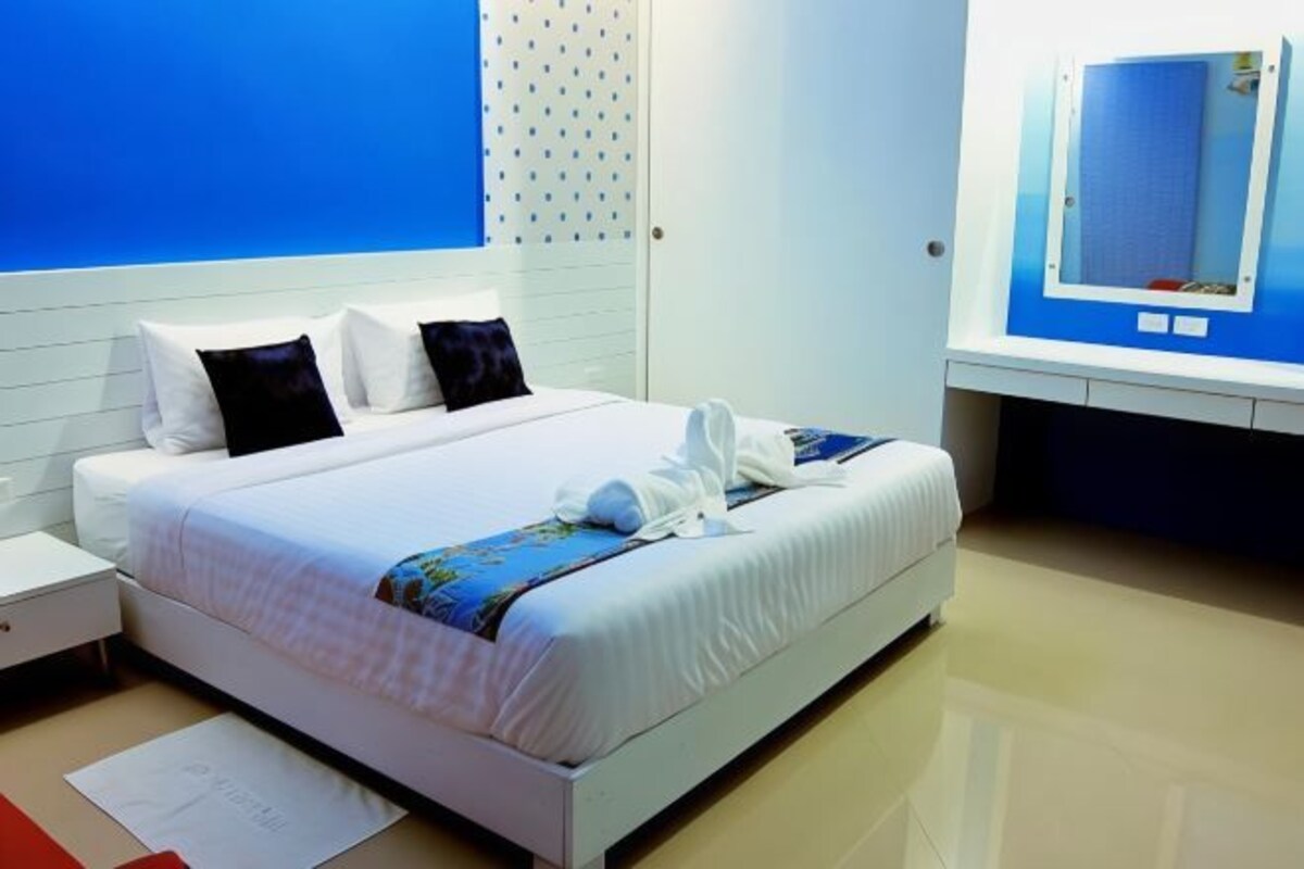 Habitación de hotel con una cama, una mesita de noche, un espejo y una pared azul.