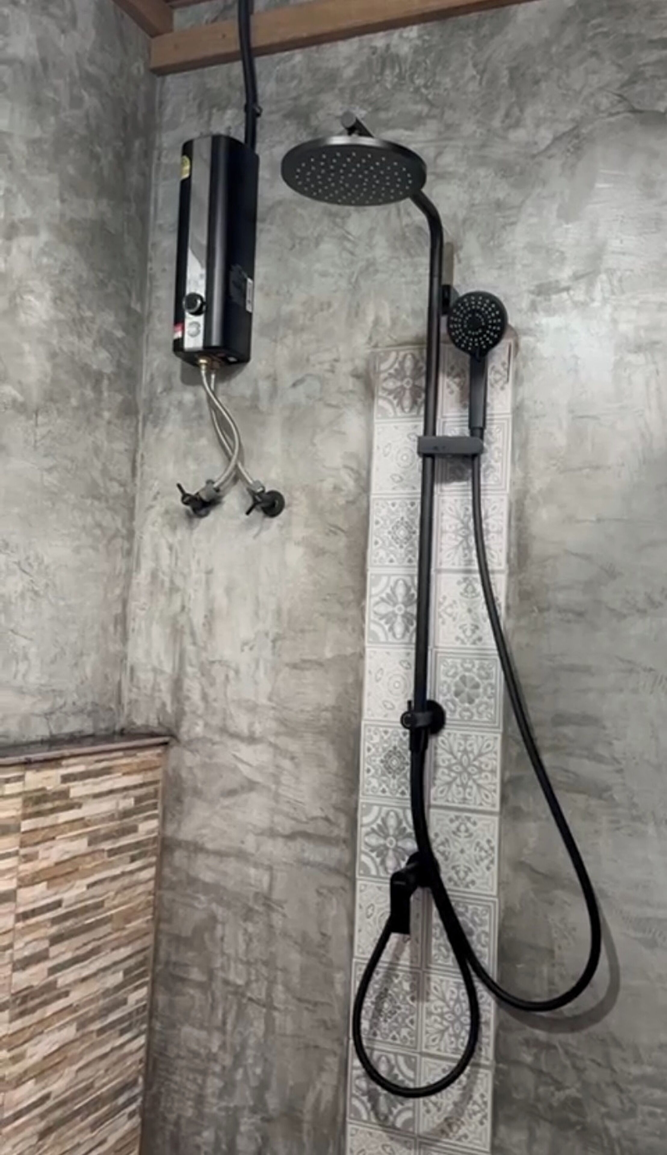 A shower with a handheld showerhead and a wall-mounted control unit.