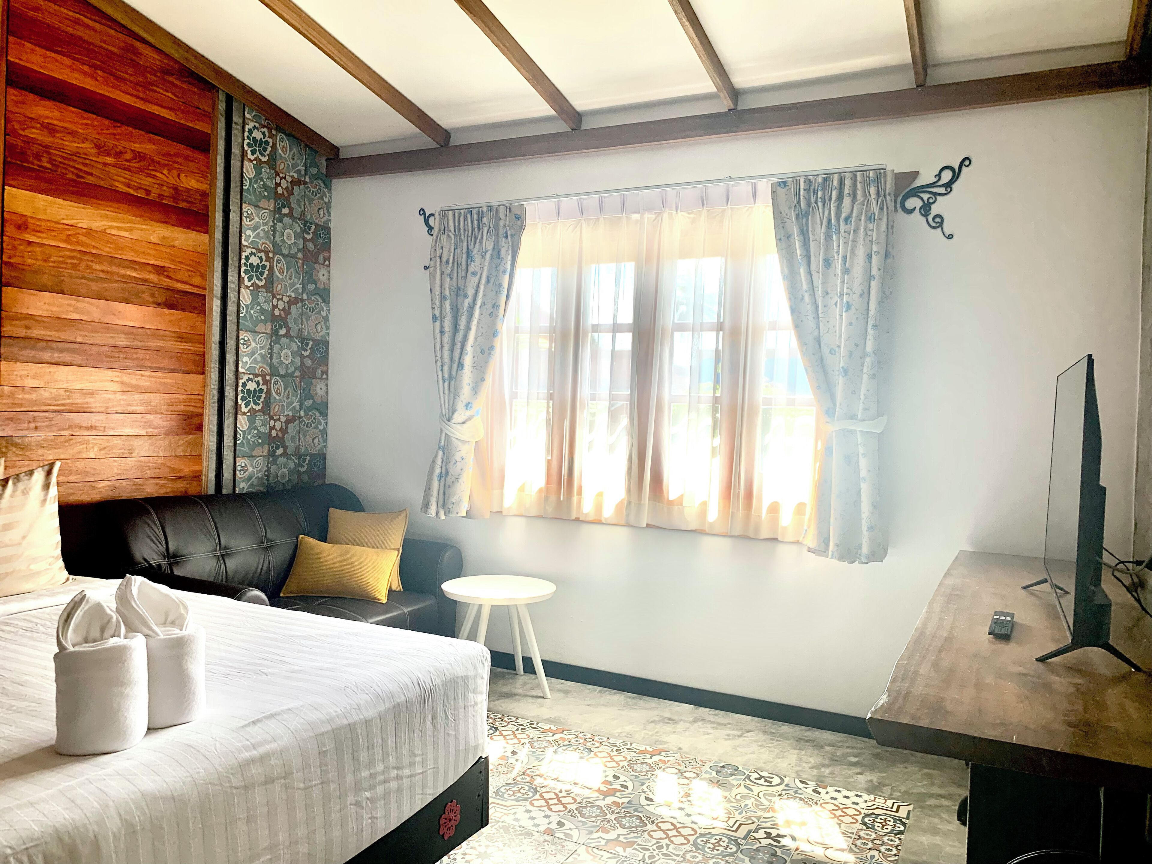 A bedroom with a bed, a sofa, a small table, and a TV.