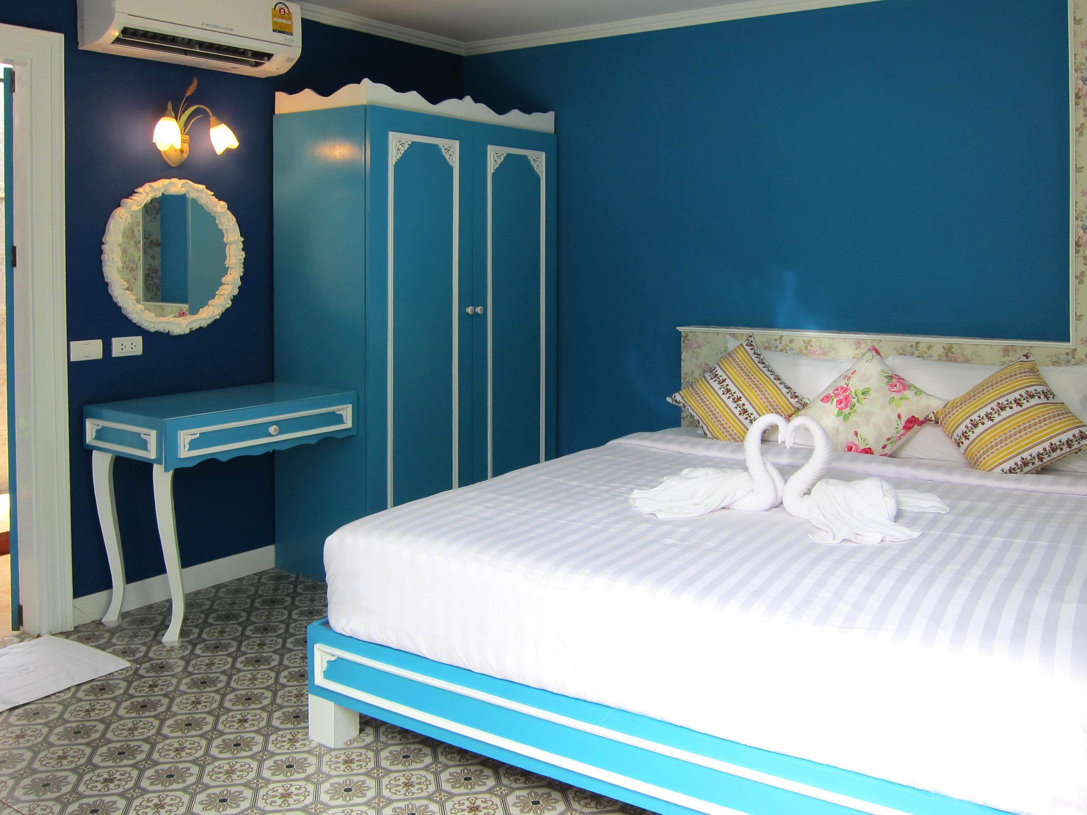 A bedroom with a bed, a vanity with a mirror, and a wardrobe.