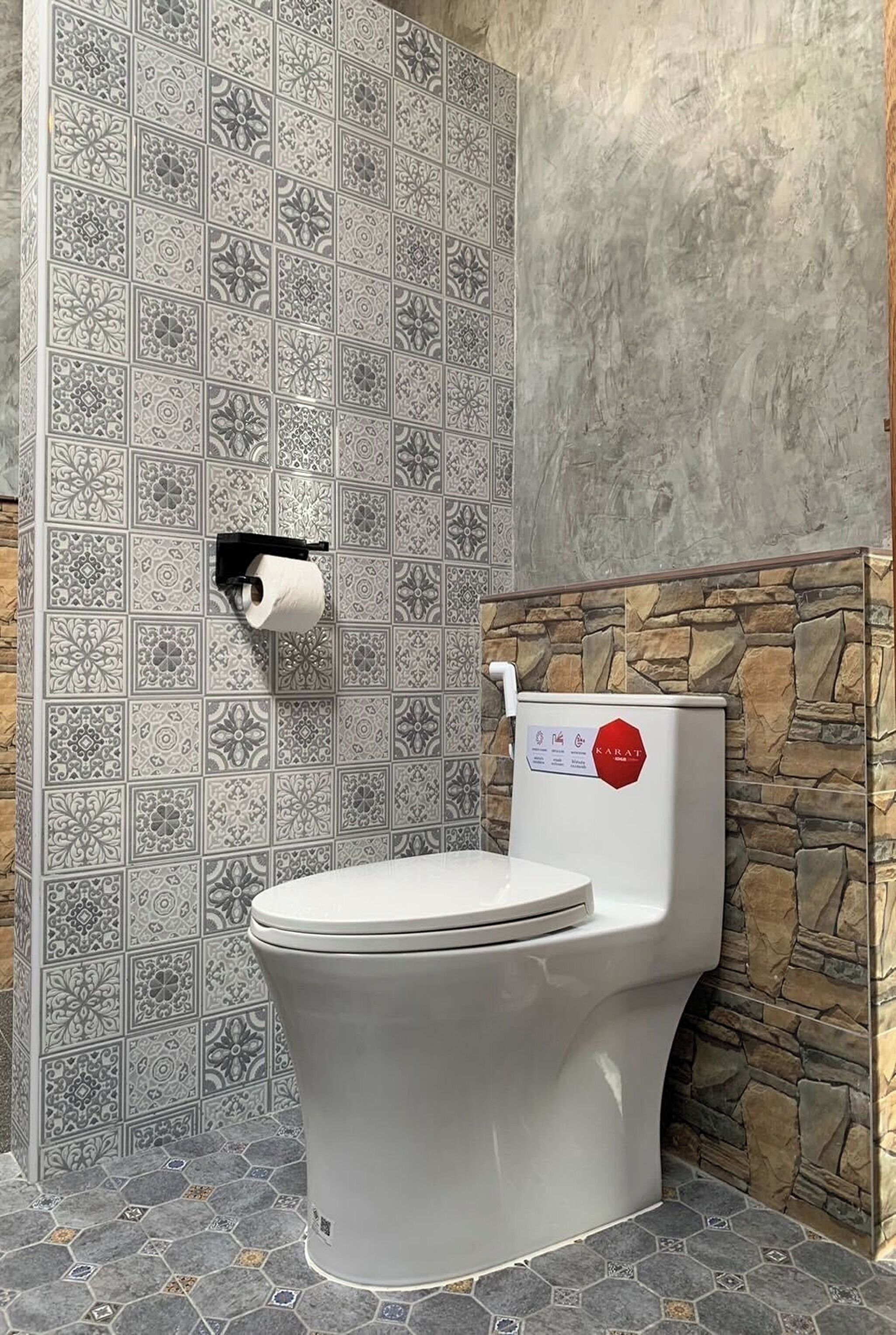 Un baño con inodoro, dispensador de papel higiénico y pared de piedra.