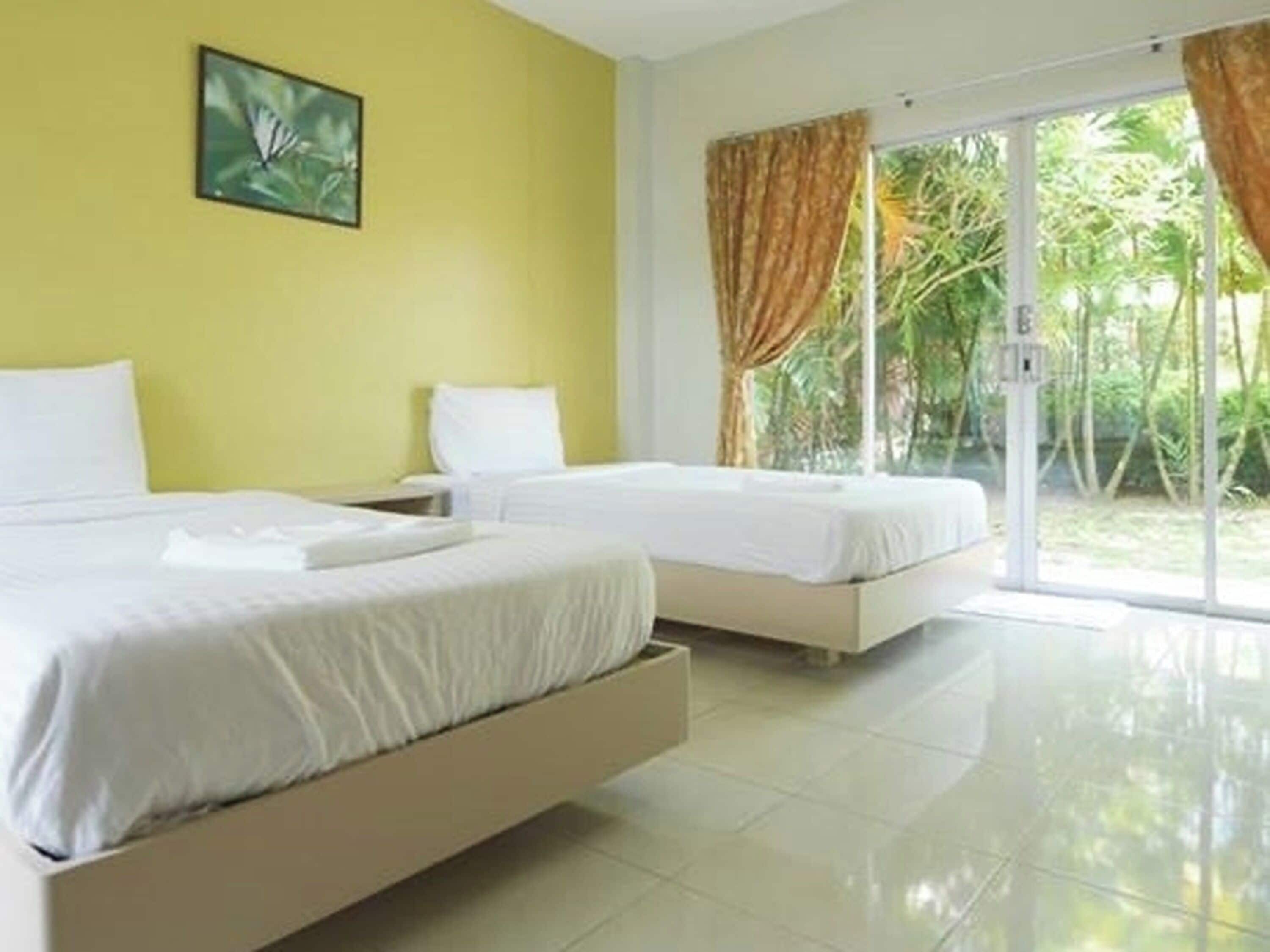 A hotel room with two beds, a large window with curtains, and a painting on the wall.