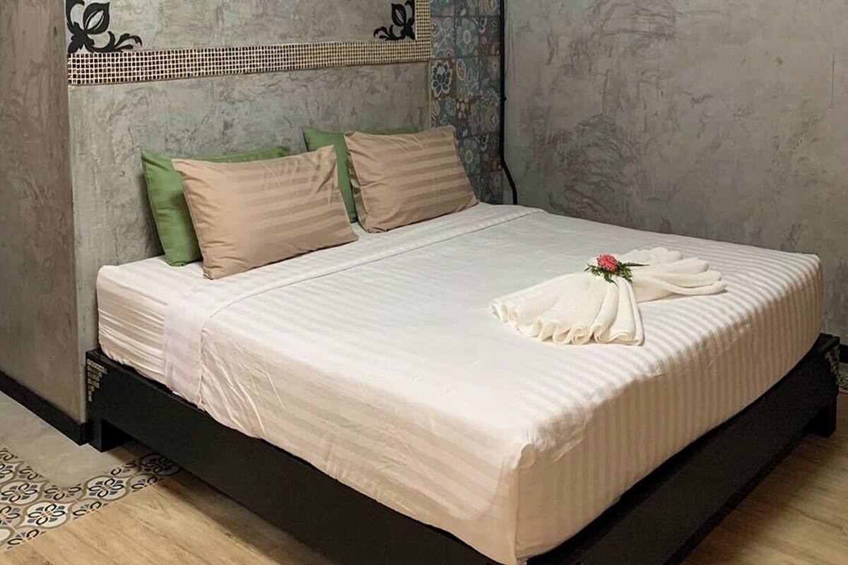 A bedroom with a bed, pillows, a decorative wall piece, and a wooden floor.