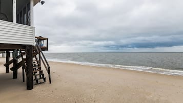 Enjoy ocean views from the deck adjacent to this beachfront property, featuring a staircase leading to a spacious outdoor area.