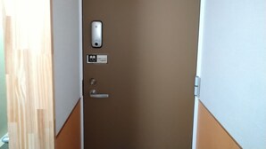 Una puerta con el letrero 201, un lector de tarjetas de acceso y un cartel que indica una habitación con cama y ducha.