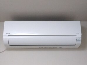 Un appareil de climatisation blanc de la marque « HITACHI », modèle « ECO ».