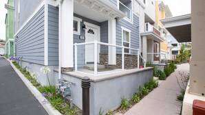 En bostadsbyggnad med en veranda, dekorativa stenelement och en liten trädgård med blommor.