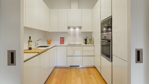 Eine moderne Küche mit weißen Schränken, einer Holz Arbeitsplatte, einem eingebauten Backofen und einer Edelstahl-Dunstesse.