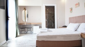 A hotel room with a bed, bedside table, desk with chair, and a shower area. - Marin Yalıkavak Hotel (Bodrum)