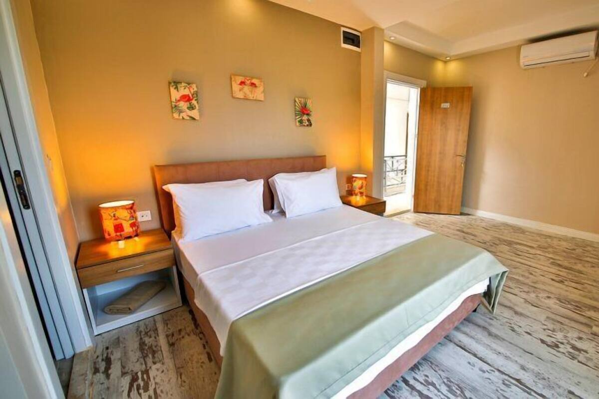 A hotel room with a bed, bedside tables, a wardrobe, and a window.