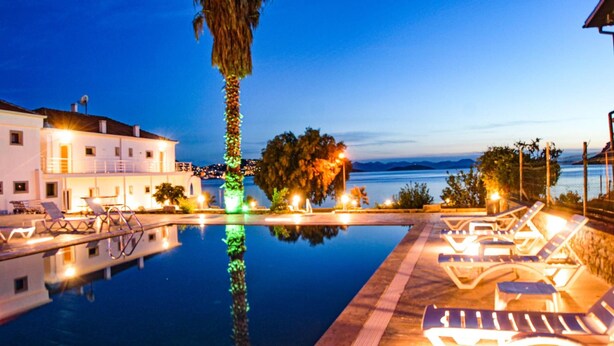 A pool area with lounge chairs and a view of the sea at dusk. - Marin Yalıkavak Hotel (Bodrum)