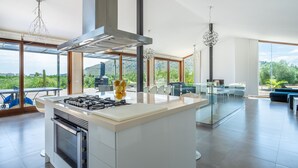 A modern kitchen with a central island, large windows, and a view of the outdoors.