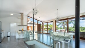 A modern kitchen with a glass dining area, large windows, and a view of the outdoors.