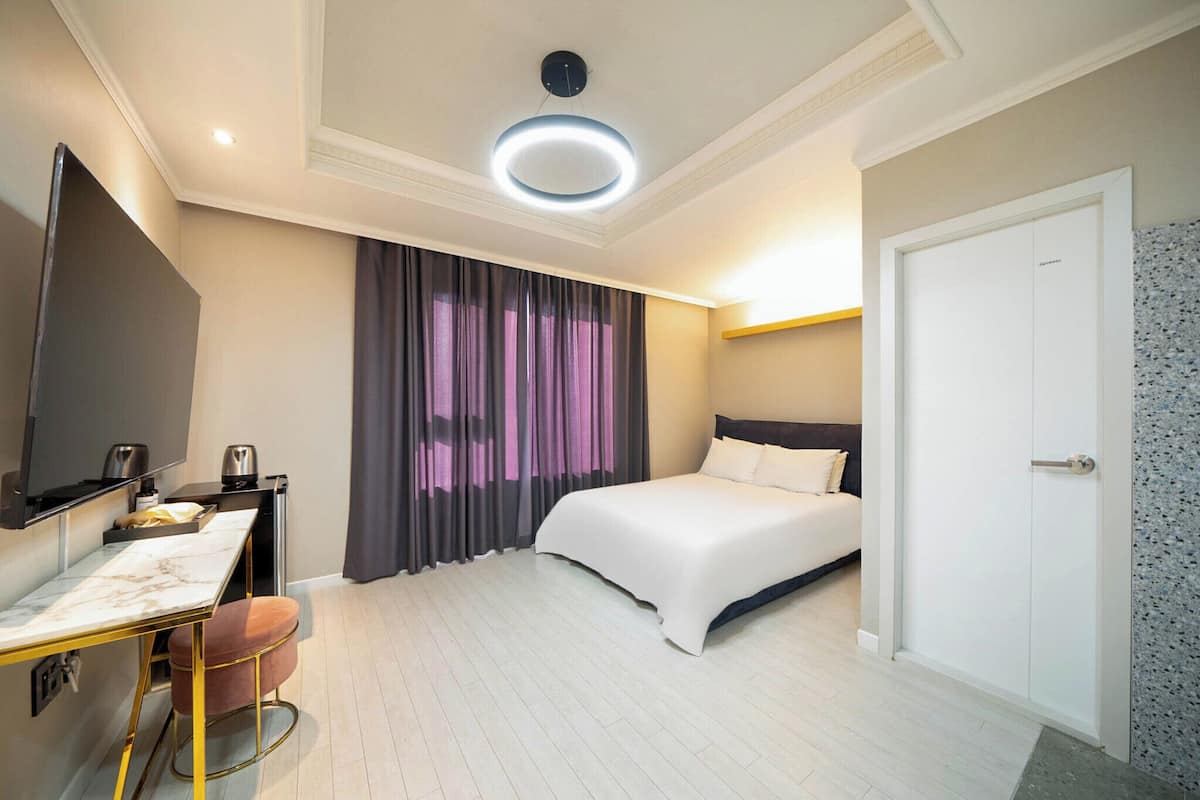 A modern hotel room with a bed, a desk, and a chair.
