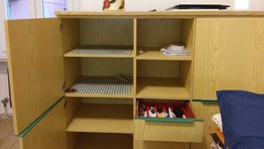 Un meuble en bois doté de plusieurs étagères et tiroirs, dont certains contiennent des objets tels qu’un bocal et des papiers.