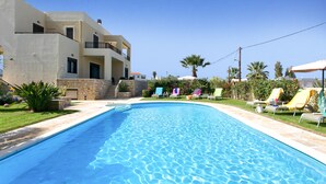 A swimming pool with lounge chairs and a building with balconies. - Villa Selena - Lux 4BD Residence (Chania)