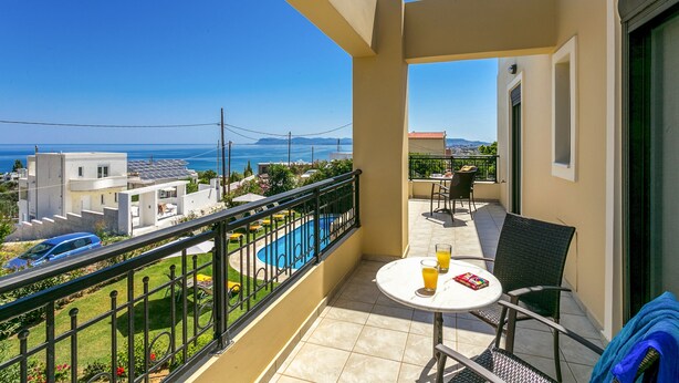 A balcony with a table, chairs, and a pool view. - Villa Selena - Lux 4BD Residence (Chania)