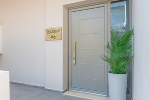 A door with a sign reading "Kismet" and a potted plant beside it.