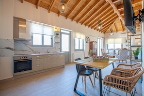 A spacious kitchen with wooden beams, a marble countertop, and modern appliances.