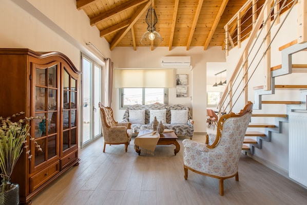 A spacious living room with a wooden staircase, a large cabinet, and a sofa set.