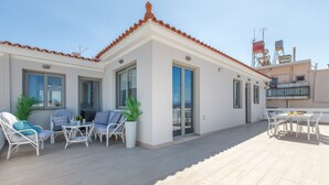 A modern building with a tiled roof, large windows, and a patio area with outdoor furniture. - Kismet Apt - Retreat to a Stylish home (Chania)
