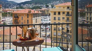 A balcony with a table set for dining, overlooking a marina and a cityscape with buildings and hills. - SunlightProperties MARINETTE - Port area, 2 Bedroom, holiday rental, sea view (Nice)