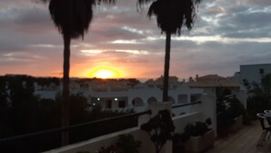 A sunset over a residential area with palm trees and white buildings. - 211- Amazing garden level Apartment - fantastic location (Albufeira)