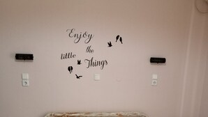 A bedroom with a bed, two bedside tables, a wall with a motivational quote, and two remote controls on the left table. - Eugenia Studios (Kefalonia)