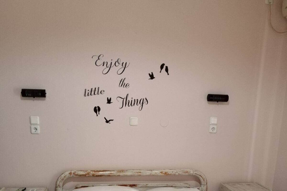 Ein Schlafzimmer mit einem Bett, zwei Nachttischen, einer Wand mit einem Motivationsspruch und zwei Fernbedienungen auf dem linken Tisch.