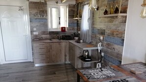 A modern kitchen with wooden cabinets, a built-in oven, and a coffee maker. - Eugenia Studios (Kefalonia)