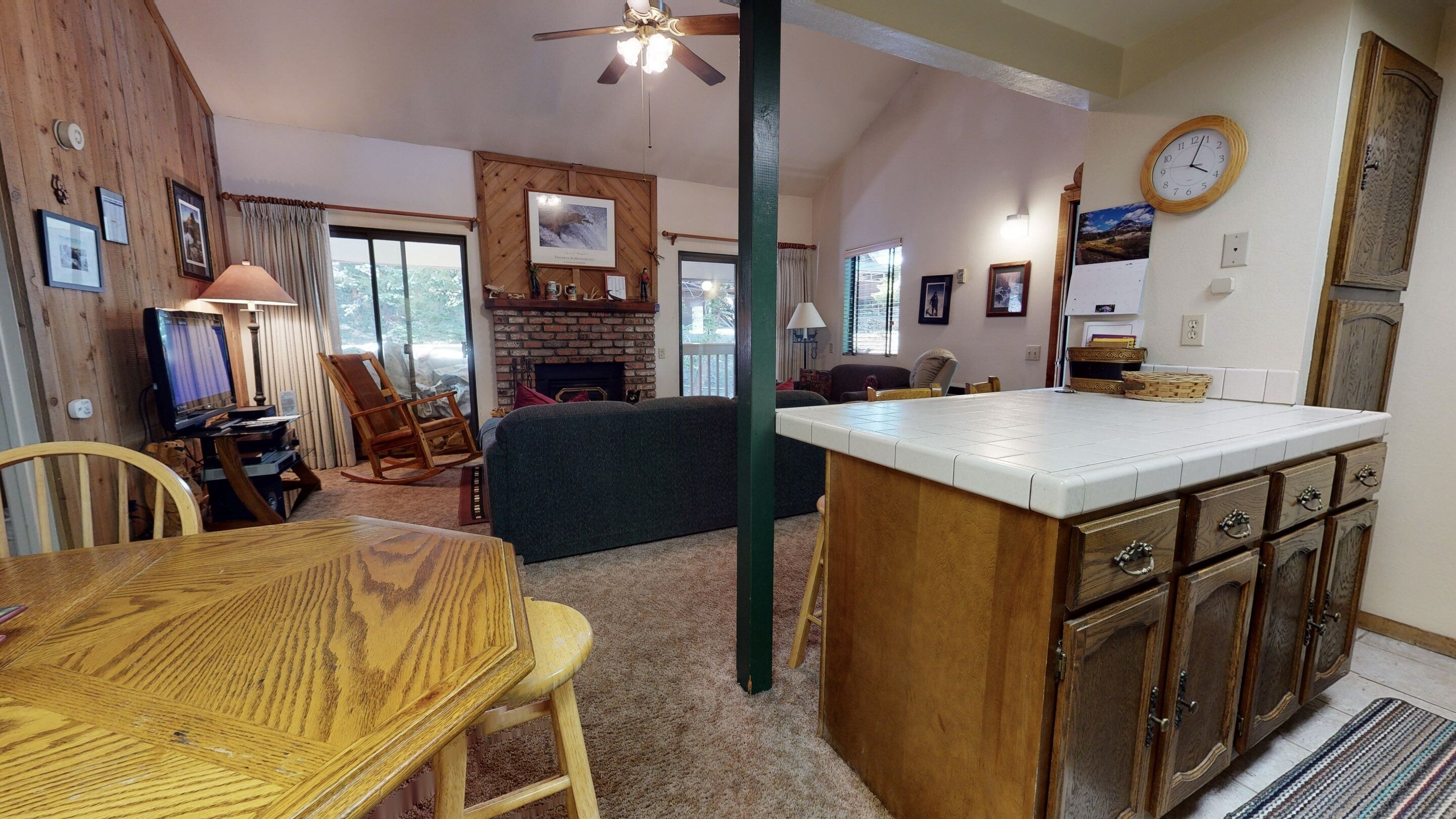 Una sala de estar acogedora con chimenea, un comedor con mesa de madera y una cocina con encimera blanca.