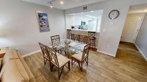 A modern kitchen with white cabinets, a microwave, and a clock on the wall. - Seacrest 204 2 Bedroom Condo by RedAwning (Fort Walton Beach)