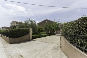 A residential street with houses, a paved driveway, and a metal fence. - Villa Barbarossa (Kastela)