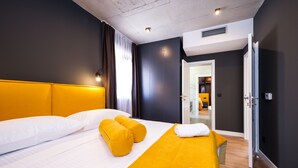 A modern hotel room with a large bed, a bright yellow accent wall, and a view of the bathroom. - Villa Antonia (Kastela)