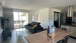 A modern kitchen with a wooden dining table, black chairs, and a built-in oven. - NEW HOUSE VILLA PORTO VECCHIO (Porto-Vecchio)
