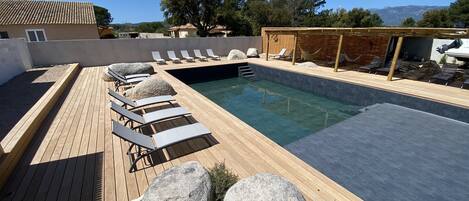 Una piscina con sillas de descanso y una terraza de madera.