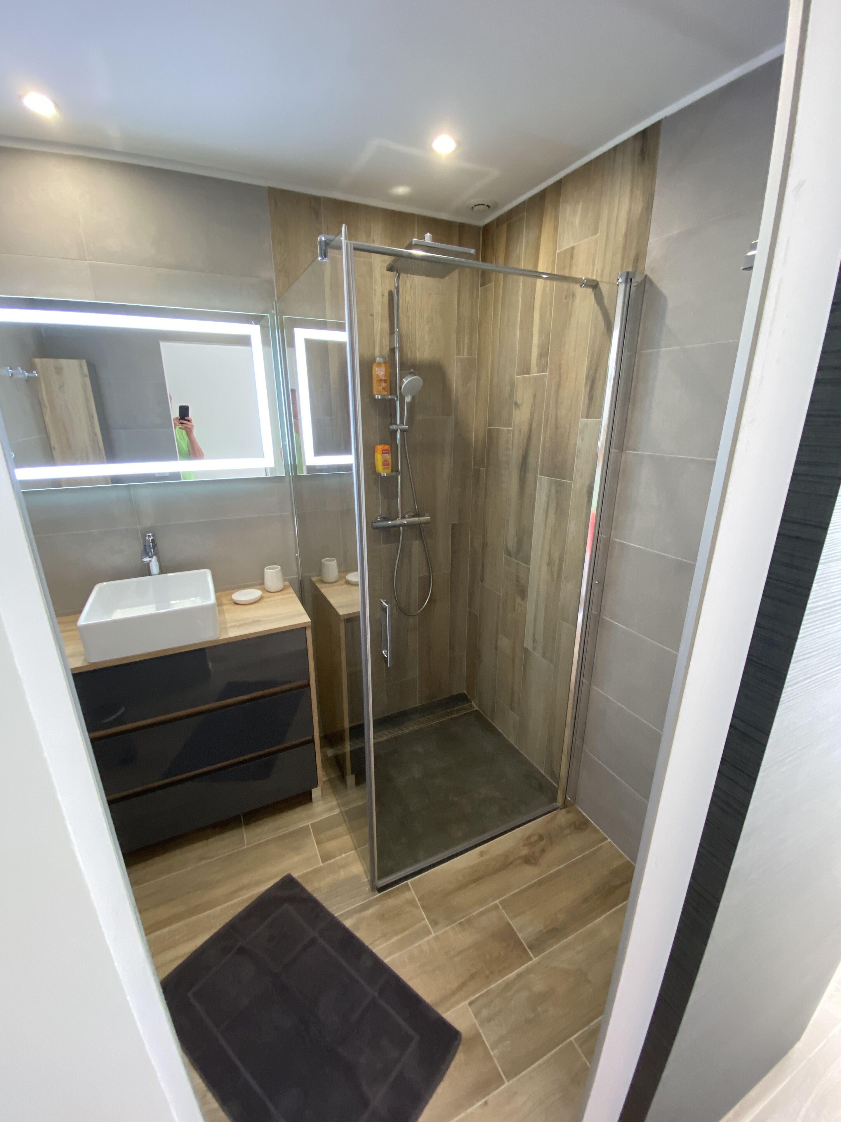 A modern bathroom with a glass-enclosed shower, a vanity with a sink, and a mirror above the vanity.