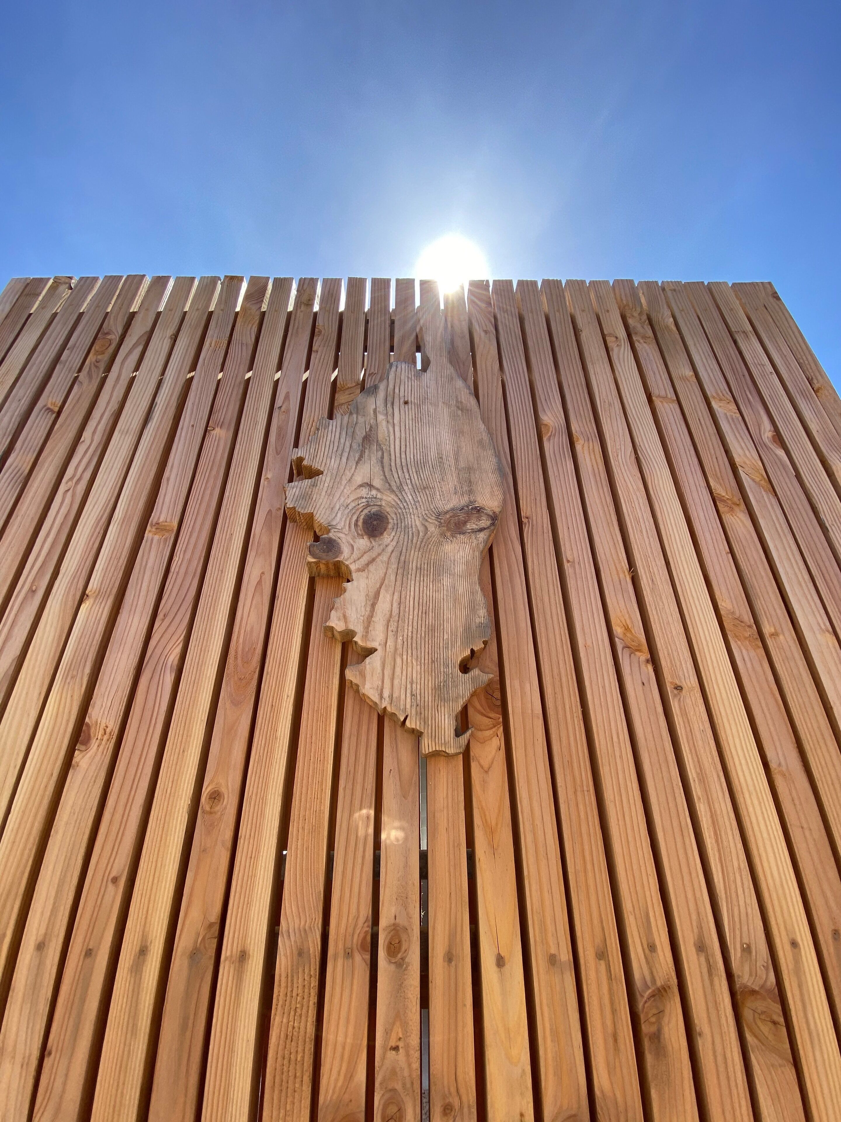 A wooden structure with vertical planks and a central carved wooden piece.
