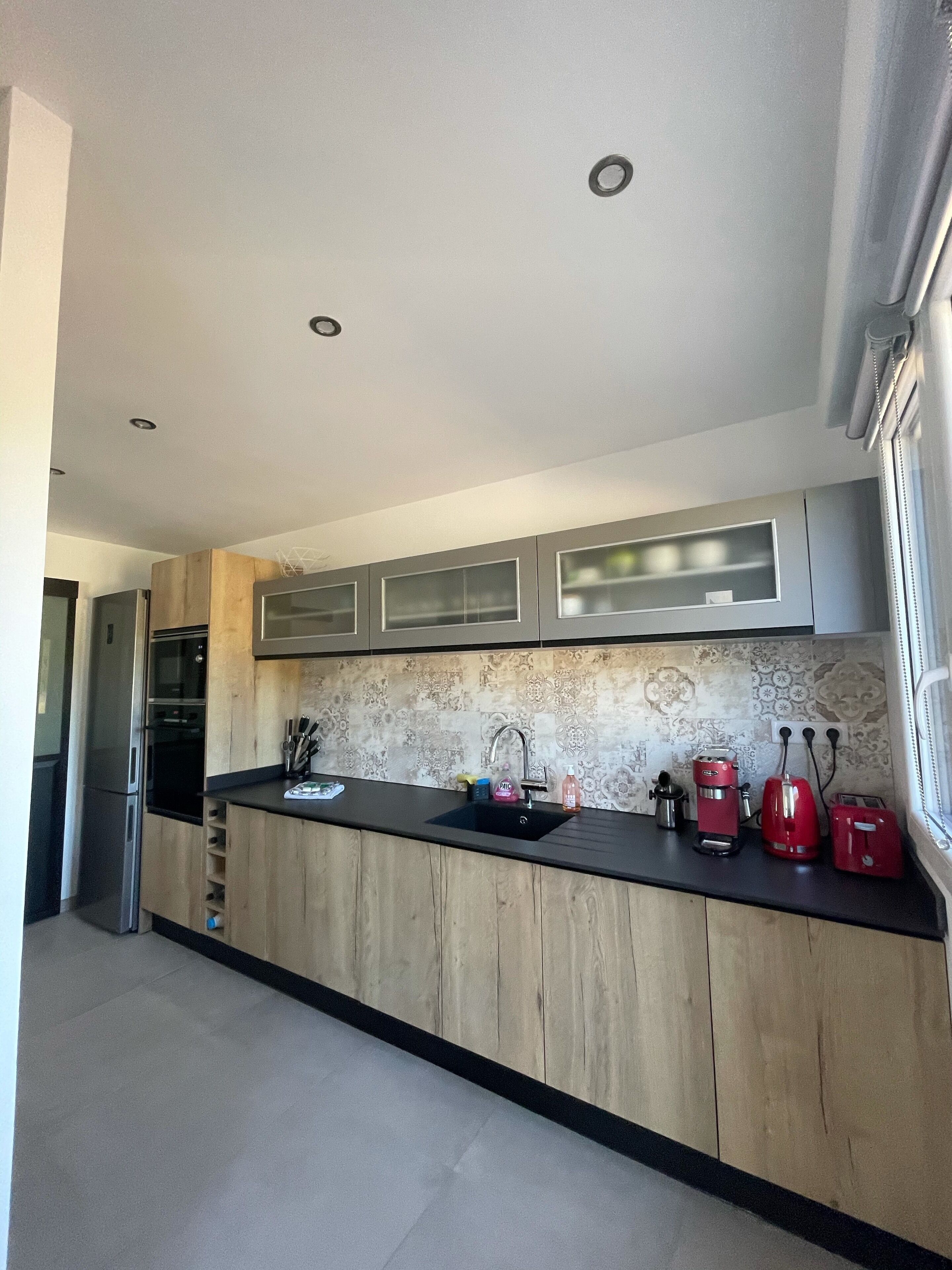 A modern kitchen with wooden cabinets, a black countertop, and stainless steel appliances.