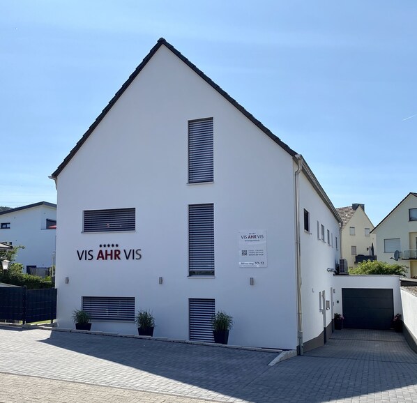 A white building with the signage 'VIS AHR VIS' and a signboard for 'VIS AHR VIS Wohnungsbau'.