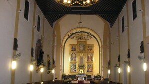 An interior of a church with rows of pews, a central altar, and a large chandelier. - such as beach (Roquetas de Mar)