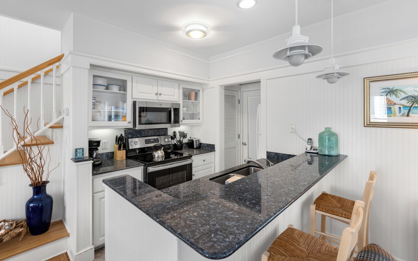 A modern kitchen with white cabinetry, a granite countertop, and stainless steel appliances.