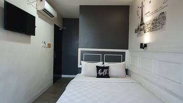 A bedroom with a bed, a flat-screen TV, an air conditioner, and a wall with a cityscape illustration.