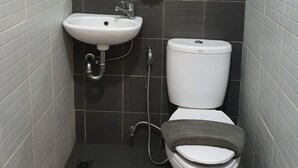 Un baño pequeño y estrecho con un lavamanos blanco, un espejo, un inodoro y un perchero para toallas.