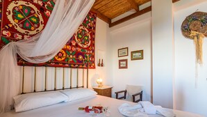 A neatly made bed with white linens, a bottle of wine, and a glass on the bed. There is a chair and a small table with a lamp. -  Eros Cozy, Panoramic Sea View, Perfect Location (Pylos-Nestoras)