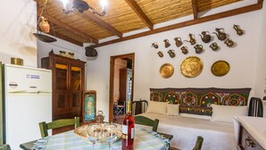 A dining area with a table set for two, a bottle of wine, and a traditional wooden cabinet. -  Eros Cozy, Panoramic Sea View, Perfect Location (Pylos-Nestoras)