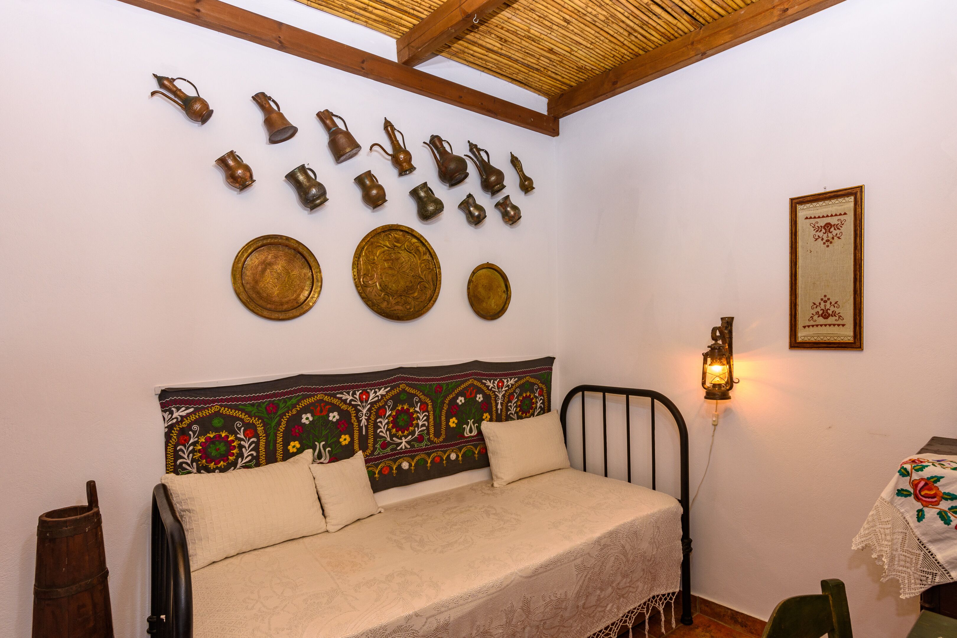 Een kamer met een bed, een wandmontage van metalen trays en een decoratief wandkleed.