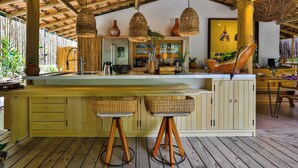 A wooden bar area with stools, hanging woven light fixtures, and a rustic ceiling. - Vila Morena Altos de Itapororoca (Porto Seguro)