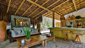 A rustic kitchen with wooden floors, a wooden bench, a sofa, and a dining table. - Vila Morena Altos de Itapororoca (Porto Seguro)
